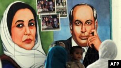 په کراچۍ کې خلک په يو نندارتون کې د ذوالفقار علي بوټو او بينظیر بوټو تصویرونه ګوري