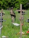 Вооруженный военный дежурит на кладбище во время захоронения останков российских военнослужащих. Луганск, подконтрольная России часть Украины, 18 мая 2023 года
