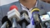 Imagine de arhivă: microfoane de televiziune plasate pe pupitrul unui politician în timpul unei conferință de presă.