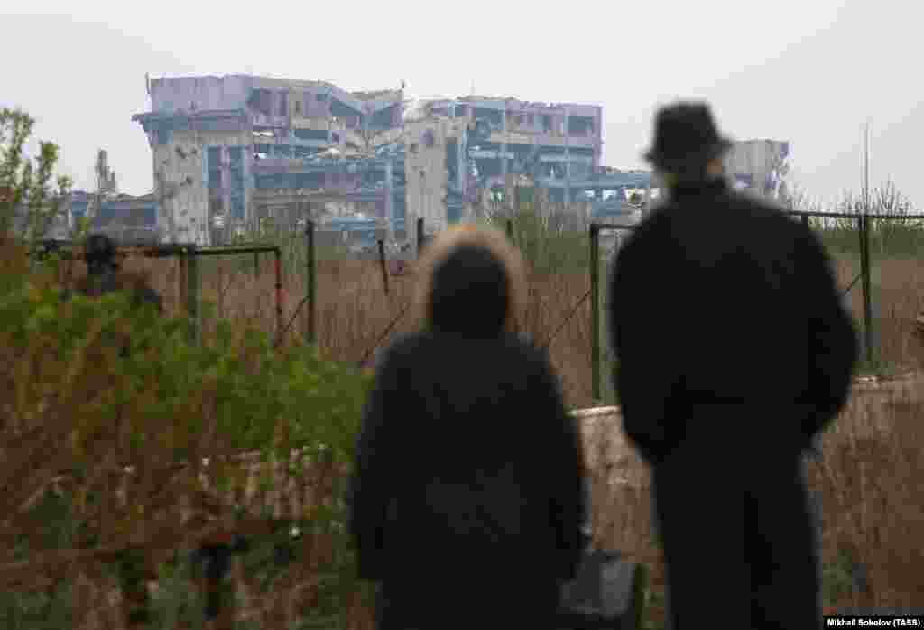 Un cuplu privește ruinele aeroportului în aprilie 2017. După ce Kremlinul a lansat invazia totală a Ucrainei în februarie 2022, întregul teritoriu al aeroportului distrus a fost preluat de forțele ruse până în noiembrie același an.