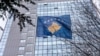 Një kalimtare rasti duke ecur ndërsa në dyert e një objekti është vendosur një flamur i Kosovës. 