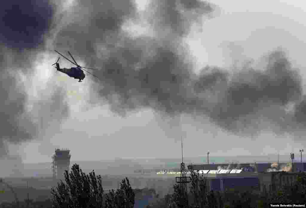 Un elicopter ucrainean de luptă trage cu tunul automat asupra aeroportului controlat de separatiști, pe 26 mai. Până pe 27 mai 2014, aeroportul a fost recucerit de forțele ucrainene, care l-au controlat timp de câteva luni, în timp ce războiul cu separatiștii susținuți de Rusia se extindea în regiunea Donbas din estul țării.