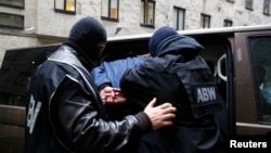Ofițerii Agenției de Securitate Internă escortează un bărbat arestat sub suspiciunea de spionaj. Varșovia, Polonia (imagine de arhivă).