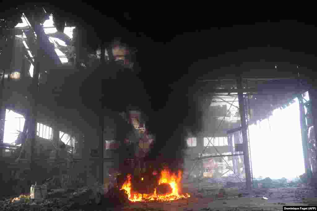 Un vehicul arde în interiorul aeroportului pe 16 octombrie. În urma luptelor corp la corp pentru controlul construcției, care au avut loc între sfârșitul anului 2014 și începutul anului 2015, aeroportul a fost redus la ruine, iar forțele susținute de Rusia au preluat în cele din urmă controlul.