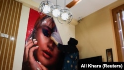 Afganistanska kozmetičarka uklanja poster u kozmetičkom salonu u Kabulu, Afganistan, 24. jula 2023.