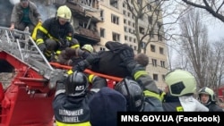 Спасатели выносят людей из обстрелянного дома на Оболони в Киеве