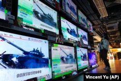 Гонконгте теледидардан Ресей әскерінің Украинаға басып кіргені туралы хабарды көріп тұрған әйел. 24 ақпан 2022 жыл.