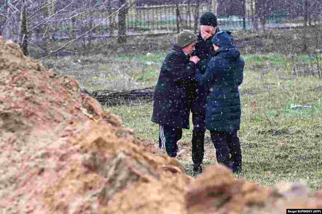 Люди плачуть біля одного із масових захоронень жертв російських військових. Буча, 3 квітня 2022 року. За повідомленням офіційного Києва, 175 загиблих людей знайшли у Бучі у різних місцях масових захоронень й катівнях 