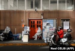 Osoblje bezbjednosti čuva ulaz u stambenu četvrt koja je pod strogim mjerama zaključavanja zbog COVID-19, Peking, 26. novembar 2022.