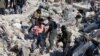 Një person mban në duar një fëmijë të nxjerrë nga rrënojat në qytetin Harim, në provincën Idlib të Sirisë. 8 shkurt 2023.