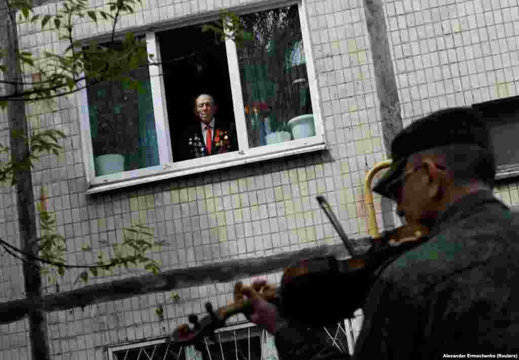 96-річний ветеран Другої світової війни дивиться із вікна своєї квартири на музикантів, які грають для нього з нагоди Дня Перемоги над гітлерівськими нацистами. Окупований російськими гібридними силами Донецьк. 9 травня 2020 року