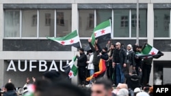 Sirijci mašu sirijskim i njemačkim zastavama tokom skupa 8. decembra u Berlinu, slaveći kraj vladavine Bašara el Asada.