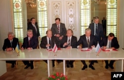 Президент України Леонід Кравчук (другий ліворуч), голова Верховної Ради Білорусі Станіслав Шушкевич (третій ліворуч) та президент Росії Борис Єльцин (другий праворуч) під час підписання Біловезької угоди, яка констатувала кінець СРСР. Біловезька Пуща, 8 грудня 1991 року