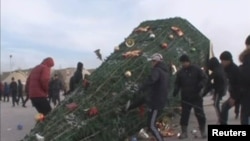 Участники протеста свалили новогоднюю елку на площади в Жанаозене. 16 декабря 2011 года.
