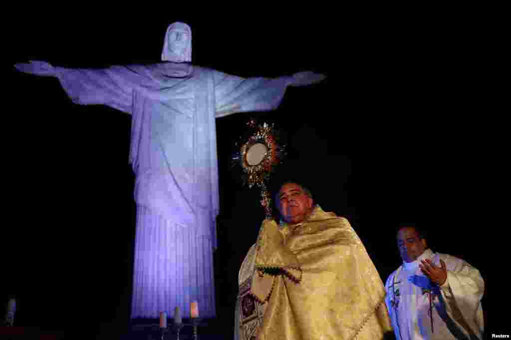 Uskrsni događaj u nedjelju kod kipa Krista Otkupitelja, u Rio de Janeiru - Nadbiskup Doma Rio O Janeiro u Rio de Janeiru drži križ nad kipom Krista Otkupitelja tokom uskrsnih nedjelja usred epidemije korona virusa (COVID-19), u Rio de Janeiru, Brazil, 12. aprila 2020. 