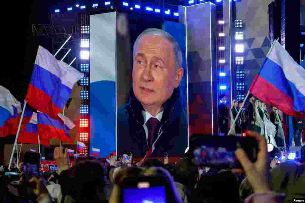 Владимир Путин, който беше обявен за победител в руските президентски избори, се вижда на видеоекран по време на митинг, който отбелязва 10-ата годишнина от анексирането на Крим от Русия. Това се случва на фона на войната, която Русия води в Украйна от 2022 г. Червеният площад, Москва, 18 март 2024 г.