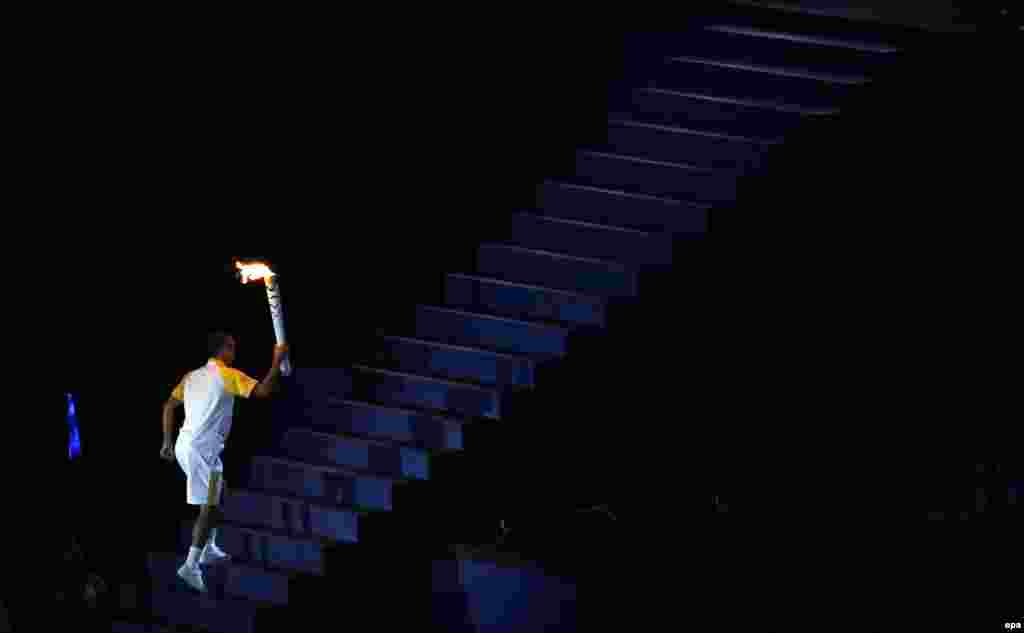 Former Brazilian marathon runner Vanderlei de Lima climbs the stairs to light the Olympic flame.