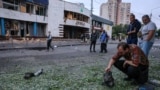 Un bărbat inspectează o bucată de motor după atacurile rusești cu drone de la Kiev, din noaptea de 20 spre 21 iulie. În fundal se vede o intrare în stația de metrou Lukianivska.