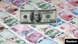 На иллюстрации изображена банкнота в 100 долларов, лежащая на банкнотах турецких лир различного достоинства, сделанная в Стамбуле, Турция, 7 января 2014 года. 