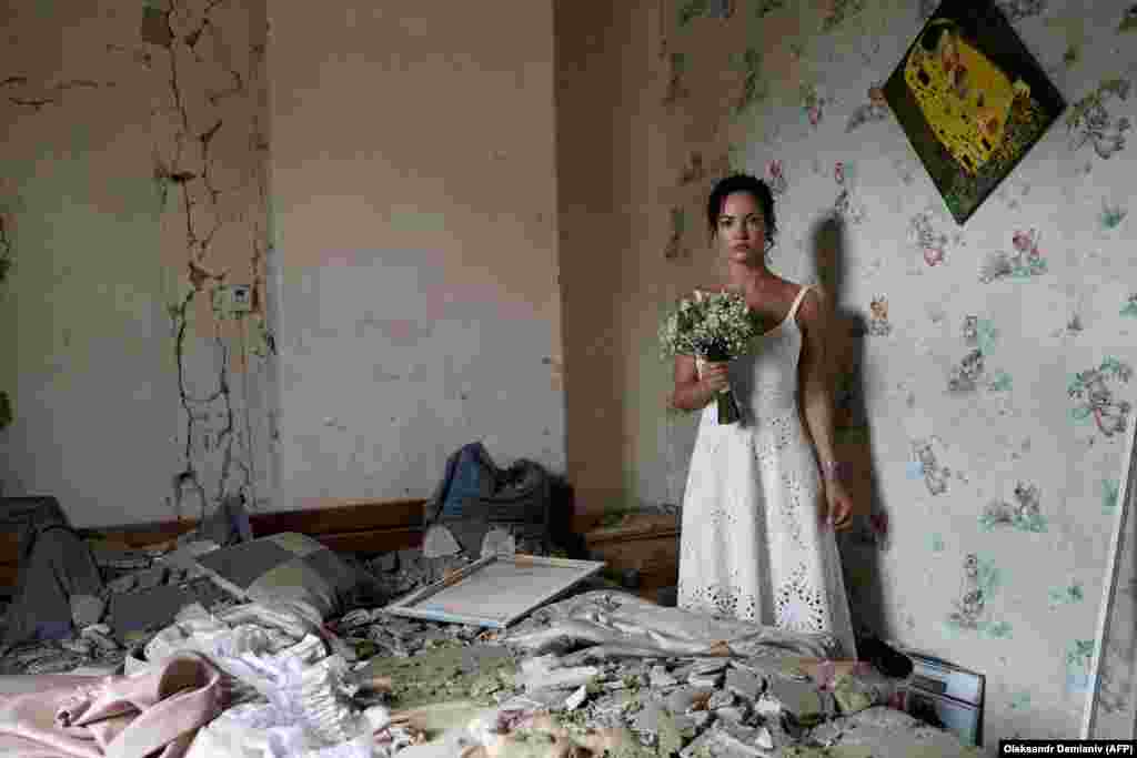 31-річна Дар'я Стенюкова позує для весільних фотографій у своїй розбомбленій квартирі у Вінниці 16 липня. Напередодні весілля дівчини російські війська обстріляли ракетами центр міста, загинули 26 людей. Однак подружжя було налаштоване рішуче: «Мій будинок був зруйнований, але не наші життя, – сказала Дар'я в коментарі AFP. – Це був зухвалий меседж усьому світу – підкреслення того, наскільки сильні українці. Ми готові одружитися, навіть якщо над нашими головами летять ракети».