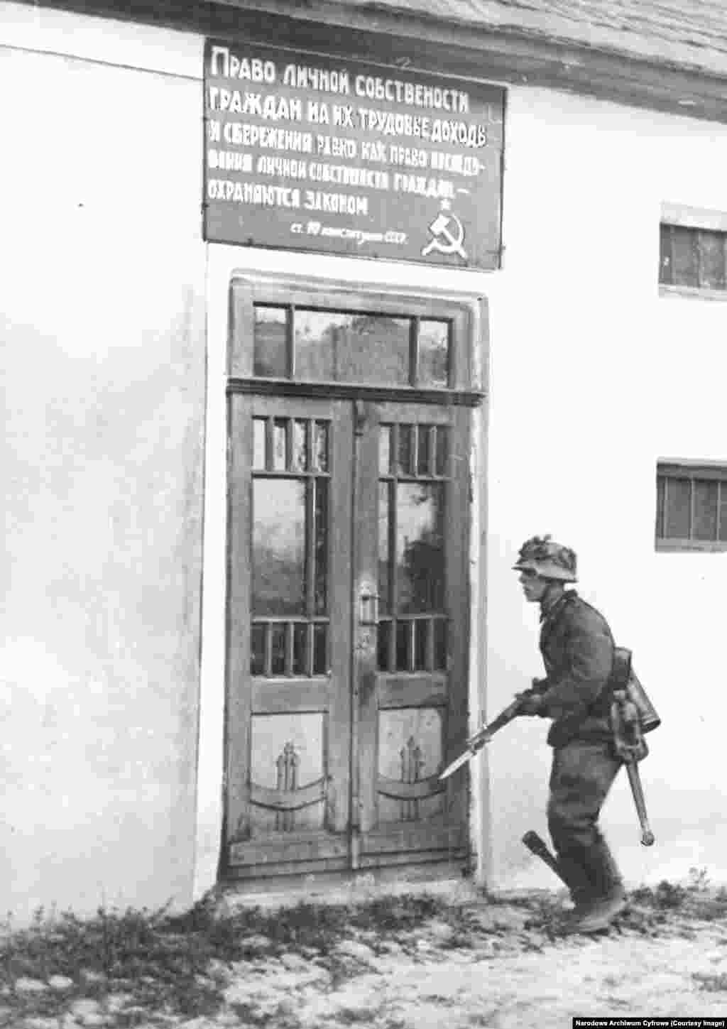 Қонышына граната қыстырған неміс сарбазы 1941 жылы маусымда совет жеріндегі елдімекеннің бірінде жүр. "Барбаросса" операциясының бір себебі нацистер басшылығы "адам санатына жатпайды" деп санаған славян халықтарына деген нәсілдік өшпенділікке келіп саятын. Нацистердің "Шығысқа арналған бас жоспары" славяндардың көбін жойып жіберуді я құлға айналдыруды, ал Совет Одағының ауқымды бөлігіне ұлты неміс адамдарды қоныстандыруды көздеді.