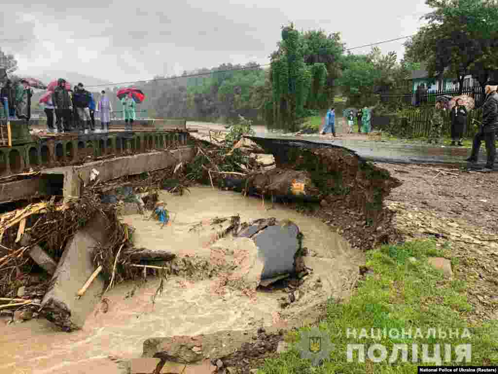 Місцеві жителі стоять на узбіччі зруйнованої потоками води дороги. Івано-Франківська область, 23 червня