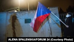 Демонстрант држи знаме на Република Чешка пред sид на руската амбасада во Прага, испрскан со кечап за време на протестот организиран од група активисти, Прага, на 17 април 2021 година.