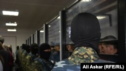 Сотрудники спецназа стоят напротив обвиняемых по делу о вооруженных нападениях 5 июня. Актобе, 28 ноября 2016 года.