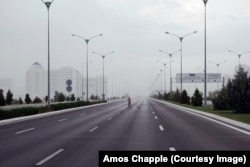 Дворник подметает одну из крупных автотрасс. Дорога, ведущая из города, пуста перед надвигающимся на город штормовым дождём.