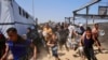Palestinieni se grăbesc să ajungă la coadă la o cantină socială din zona Mawasi din Khan Yunis, în sudul Fâșiei Gaza. 22 iulie 2025.<br><br>Potrivit ONU, aproximativ 900.000 de copii din Gaza suferă de foame, iar 70.000 dintre ei sunt în stare de malnutriție