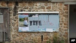 Izborni plakati, na nekima iskrivljeni grafitima "Barela, ne želimo te", u Gazeranu, južno od Pariza, juli 2024.