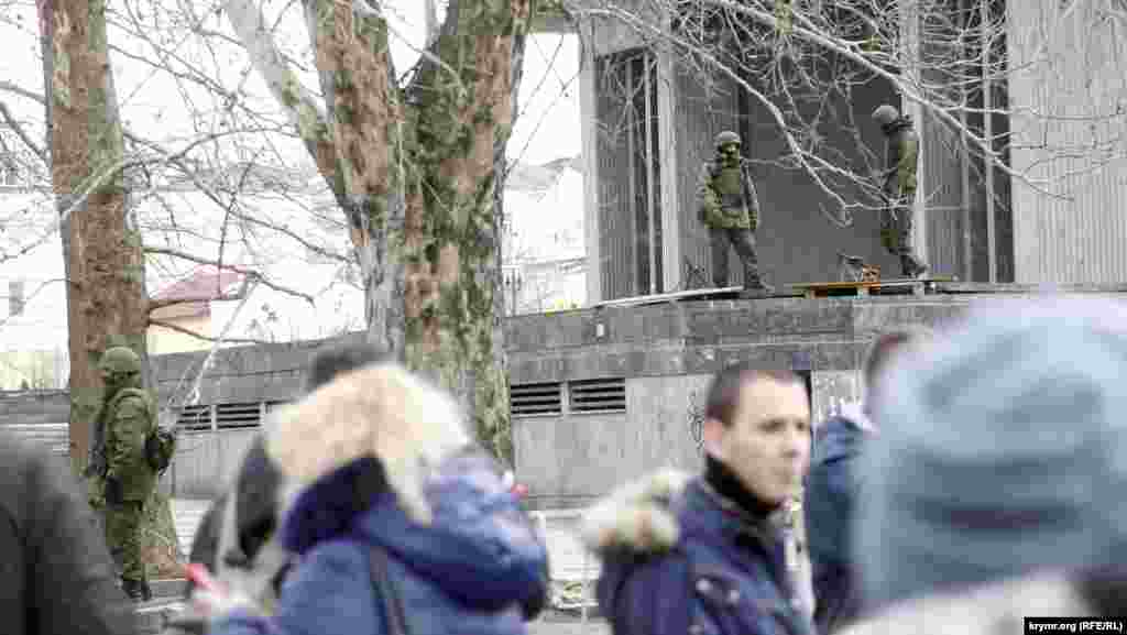А у Верховной Рады Крыма рядом с четырьмя пулеметами Калашникова переминались с ноги на ногу четыре пулеметчика. На высоких мраморных парапетах бассейнов перед зданием были положены два деревянных поддона, первоначально притащенных активистами от ближайшего супермаркета для строительства баррикад. На этих паллетах и стояли пулеметы, по два на каждом. Коробки с патронами были пристегнуты к пулеметам, ленты заправлены в приемники. Несколько спецназовцев стояли перед парапетами, а перед ними, в свою очередь, густой цепью расположились «ополченцы». Подойти ближе, чтобы сделать фотографию, активисты не позволили.